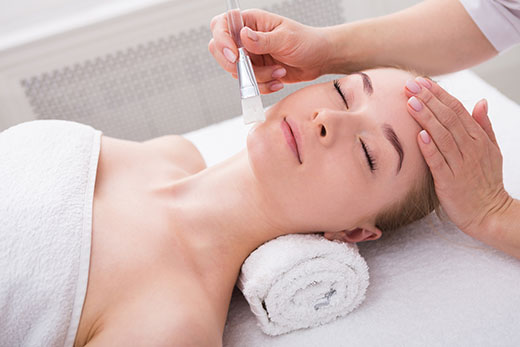 A woman receiving a facial treatment at a spa, relaxing on a treatment table with soothing ambiance around her.