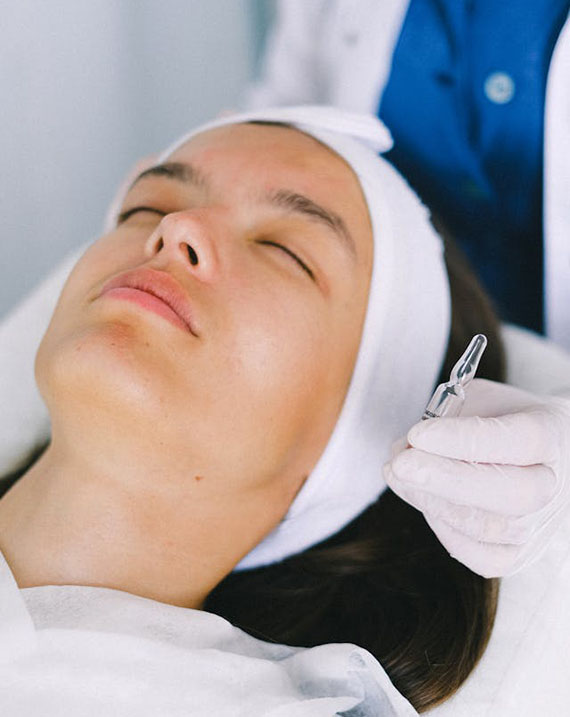 A woman receiving a facial treatment in a spa setting, relaxing with a serene expression on her face.