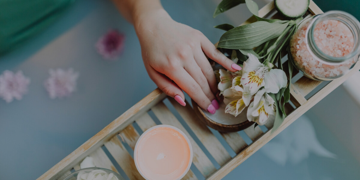 A woman's hands hold a tray adorned with colorful flowers and lit candles, creating a warm, inviting atmosphere.