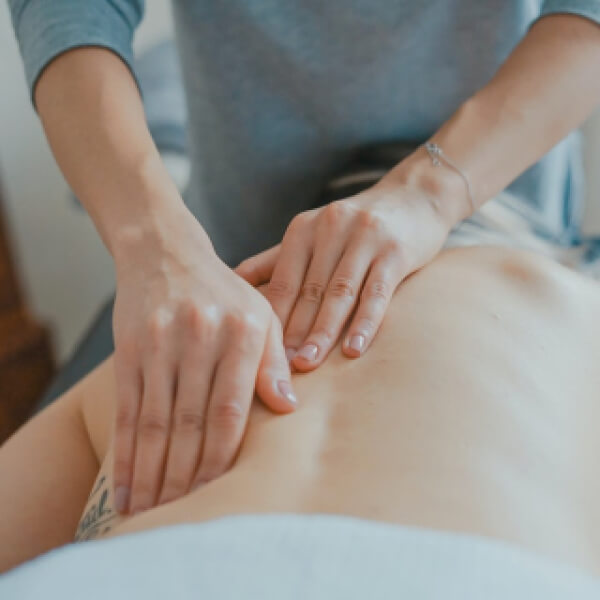 A woman receiving a back massage in a serene room, promoting relaxation and wellness.