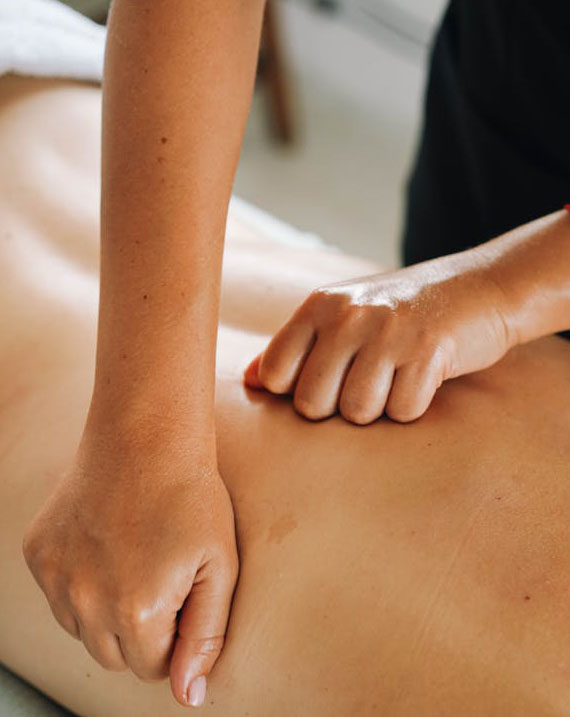 A person receiving a back massage, lying face down on a massage table in a serene environment.