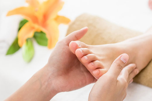 A person receiving a relaxing foot massage in a serene setting, with hands gently working on their feet.